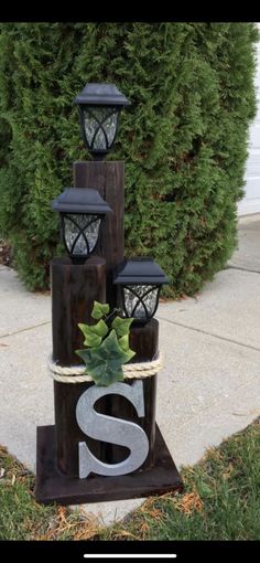 some lights are sitting in front of a bush and sidewalk with the letter s on it