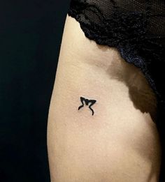 a small black bow tattoo on the side of a woman's right thigh,