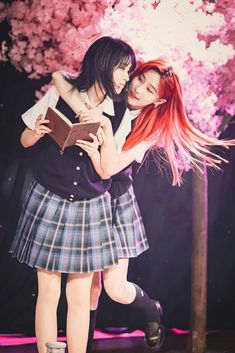 two girls are hugging each other while holding an open book