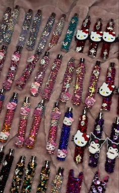 many hello kitty bottles are lined up on a table with sequins and bows