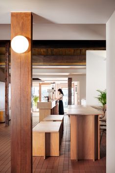 a woman is standing in the middle of a room with wooden floors and counter tops