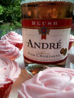 cupcakes with pink frosting next to a bottle of wine