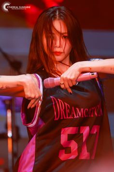 a woman holding onto a black shirt with pink writing on it and her arm in the air