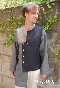 a man standing in front of a stone wall wearing a gray and black jacket with buttons