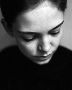 a black and white photo of a woman looking down at her cell phone while wearing a sweater