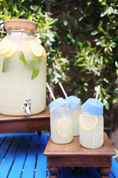 two mason jars filled with lemonade sit on a table next to a wooden tray