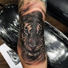 a black and white tiger tattoo on the arm, done by an expert in body art