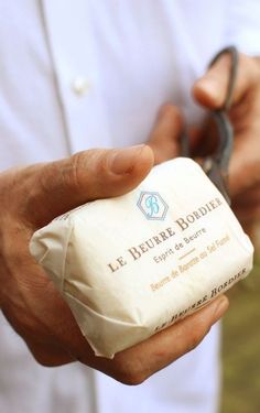 a man is holding a bar of soap and shears in his left hand while wearing a white shirt