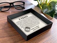 a pair of black glasses sitting on top of a wooden table next to a book