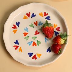 two strawberries sit on a colorful painted plate