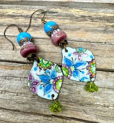 the earrings are decorated with colorful flowers and bead details on wooden planks as if they were handmade