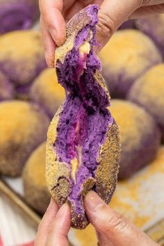 a person holding up a doughnut with purple frosting