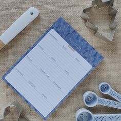 some cookie cutters and paper on a table with baking utensils next to it