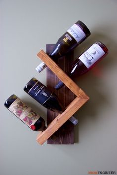 three bottles of wine are sitting in a wooden holder on the wall next to each other