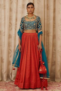 Teal blue blouse with all-over block print and zardozi embroidery. Paired with embroidered burnt orange lehenga and dupatta.
Component: 3
Printed, Embroidered
Neckline: Round
Sleeve Length: Half
Fabric: Raw Silk, Cotton Satin, Net 
Color: Blue, Orange
Cutout at the back with tie-up belt
Lehenga: Drawstring closure
Note: Potli shown in the image is not for sale - Aza Fashions Burnt Orange Lehenga, Teal Blue Blouse, Orange Lehenga, Embroidered Wedding, Embroidered Neckline, Indian Fashion Designers, Orange Fabric, Satin Skirt, Designer Gowns