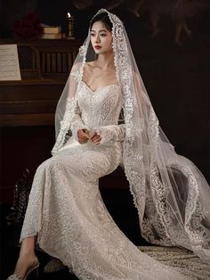 a woman wearing a wedding dress and veil sitting on a chair in front of a piano