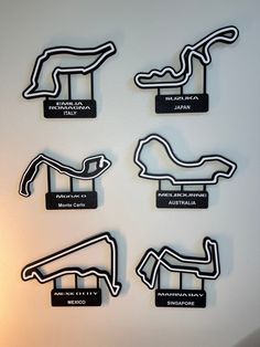 four black and white race car shaped magnets are on the wall next to each other