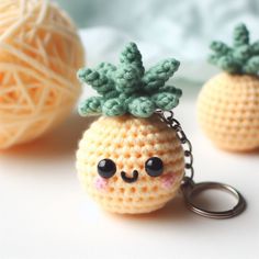 crocheted pineapple keychain with eyes and nose on white surface next to ball of yarn