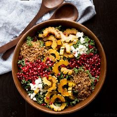 a wooden bowl filled with vegetables and meat on top of a table next to a spoon