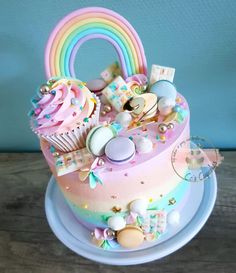 a multi - colored cake with lots of decorations on it and a rainbow shaped topper