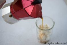 someone pouring something into a small glass with food in it and an umbrella on top