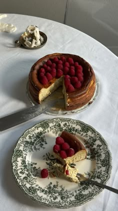 a cake with raspberries is on a plate next to a knife and fork