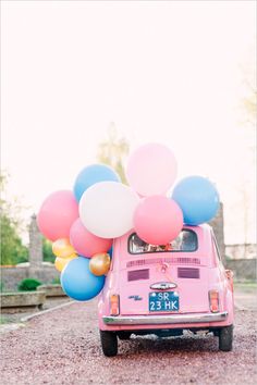 a pink car with balloons attached to it