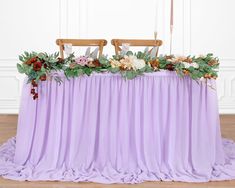 the table is covered with purple cloth and flowers