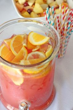 a glass jar filled with orange slices next to paper straws and cups full of fruit