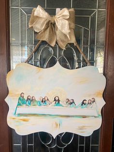 a door hanger with a painting of the last supper on it and a bow