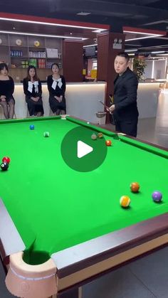 a group of people standing around a pool table