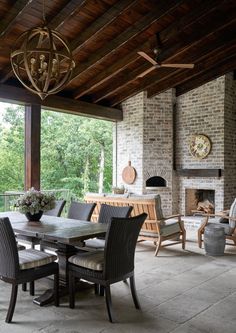 an outdoor dining area with chairs, table and fireplace