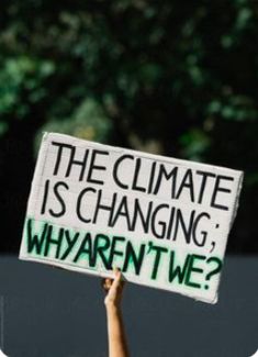 a person holding up a sign that says the climate is changing why aren't we?