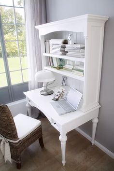 a white desk with a laptop on top of it next to a chair and window