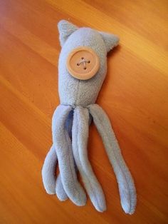 an octopus stuffed animal with a button on it's head sitting on a wooden floor