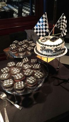 a table topped with lots of cupcakes covered in frosting and decorated with checkered flags