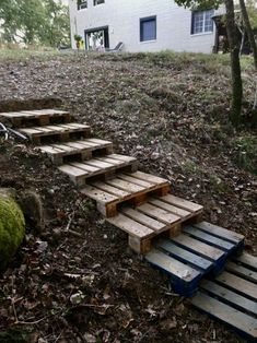 some steps made out of pallets in the woods next to a house and trees