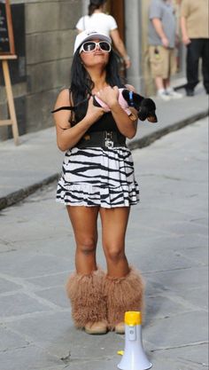 a woman is standing on the sidewalk with her dog