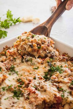 a casserole dish with meat and vegetables being scooped from the casserole