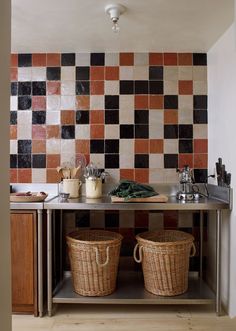 two wicker baskets sit on top of a counter in front of a tiled wall