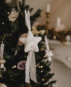 a small christmas tree decorated with white and pink flowers, stars and personalized ornaments