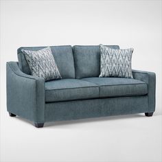 a blue couch with two pillows on it's back and one arm facing the camera