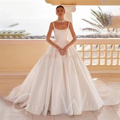 a woman in a white wedding dress standing on a balcony with her hands on her hips