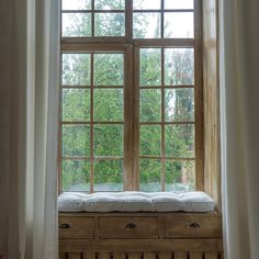 an open window with a bench in front of it and trees outside the window sill