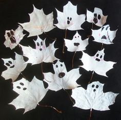 a group of white leaves with faces drawn on them and ghost eyes painted on them