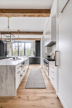 a large kitchen with white cabinets and marble counter tops, along with an area rug that matches the hardwood flooring