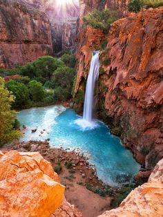 the sun shines brightly over a waterfall and blue pool in grand canyon national park