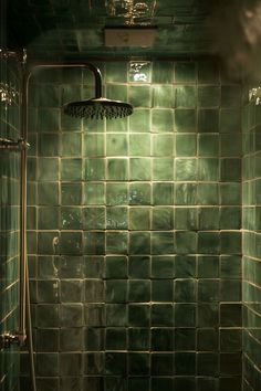 a green tiled bathroom with a shower head