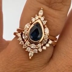 a woman's hand holding a ring with a blue tear shaped stone on it