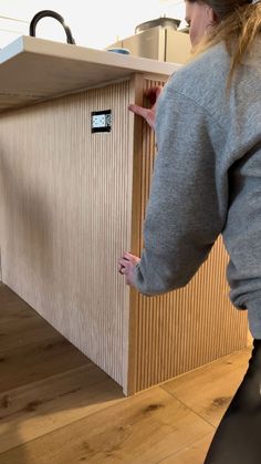 a woman is standing in front of a counter and looking at something on the wall